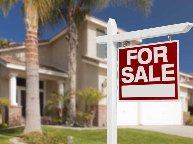 Home For Sale Real Estate Sign in Front of Beautiful New House. Home For Sale Real Estate Sign in Front of Beautiful New House.