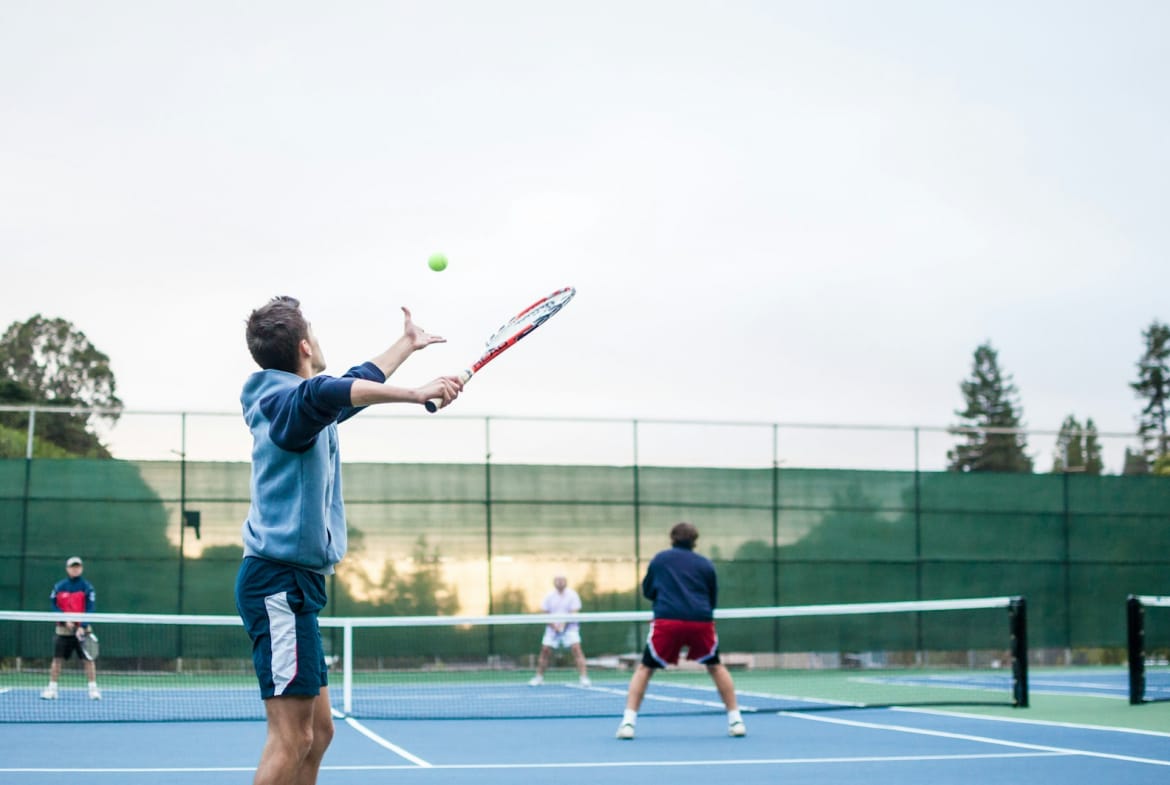four men playing double tennis during daytime