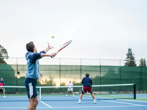 four men playing double tennis during daytime